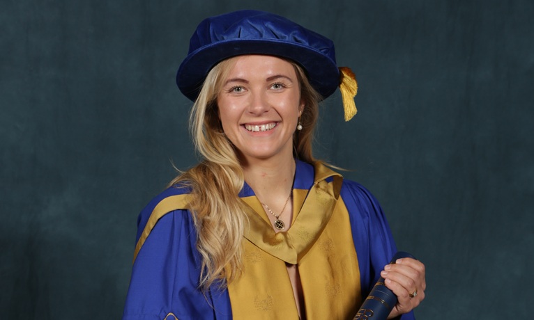 Zoe Stratford smiling at the camera wearing her ceremonial gown and cap