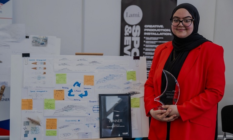 Amel holding her trophy in front of her winning design