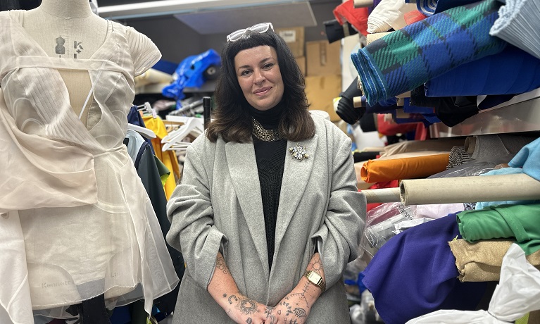 Rebecca Ryder-Caddy in a fashion workshop surrounded by materials and next to a dummy