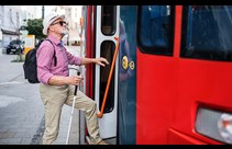 A picture of a man wearing dark glasses stepping onto a bus