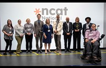 Representatives of the NCAT consortium group in front of the NCAT logo