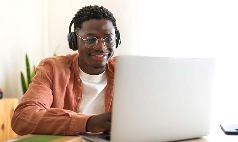 A student wearing headphone looking at a laptop