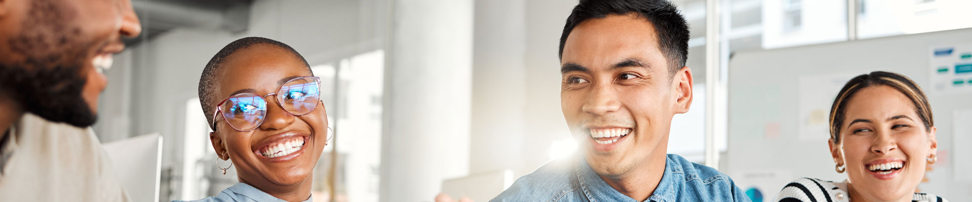 Teachers in a classroom sitting around a laptop talking.