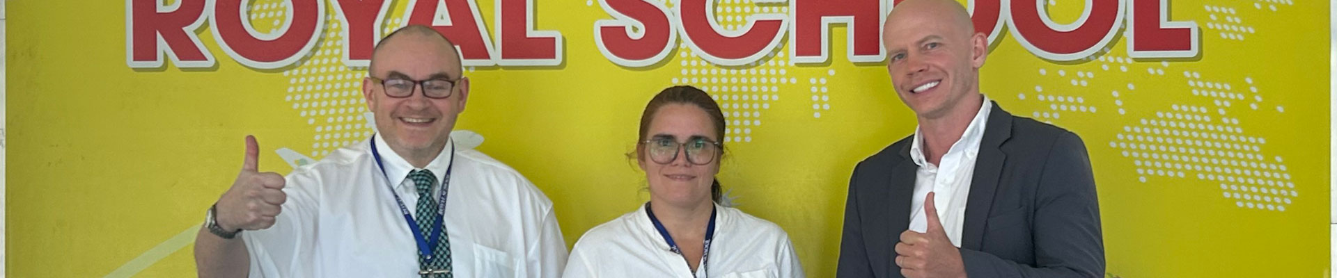Joshua James in a suit with two other people, smiling at the camera and giving a thumbs up.