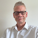 A close up portrait of Mark Cavill with a plain background