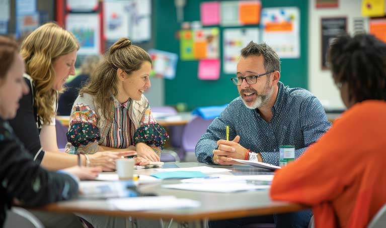 Group of teachers sitting around a table in a classroom.