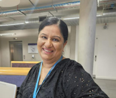 Headshot of Neelam Raju in an office, smiling at the camera.
