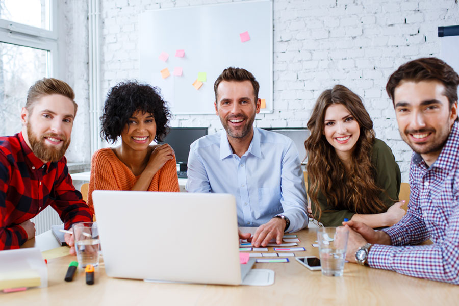A group of people at a table with an open laptop in front of them.