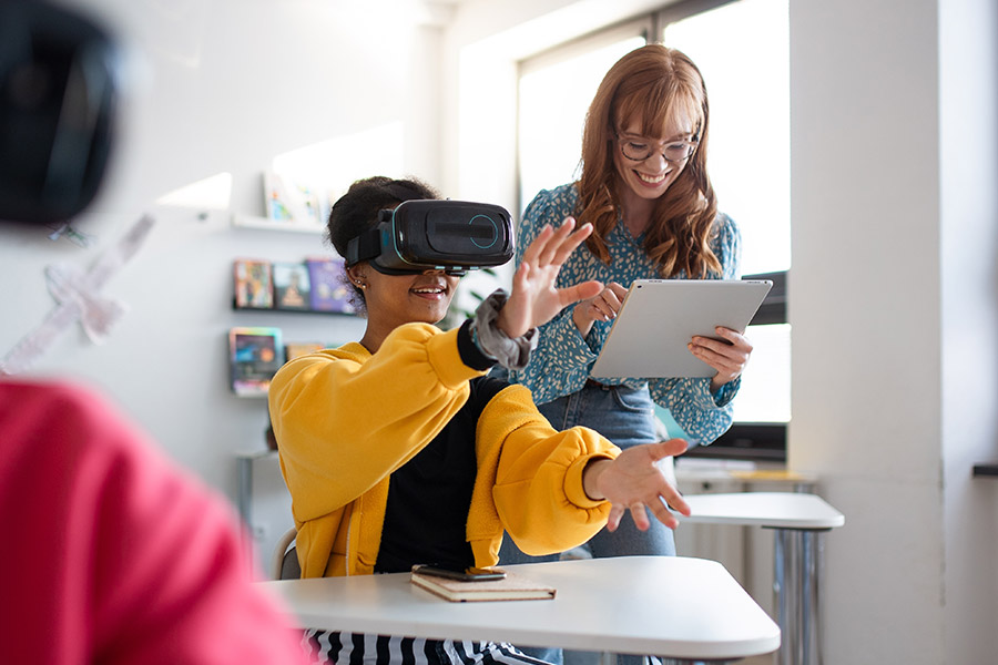 A young teacher with a student using a virtual reality headset.