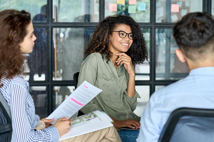 Three people sat together against a glass window with sticky notes on it.