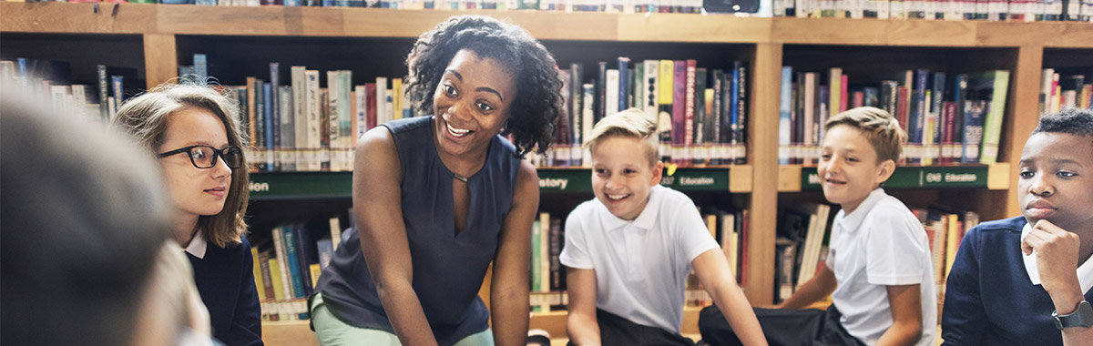 A teacher sat on the floor with her students in a library.