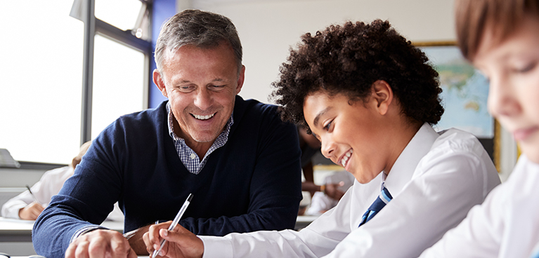 Teacher helping a pupil at a desk 