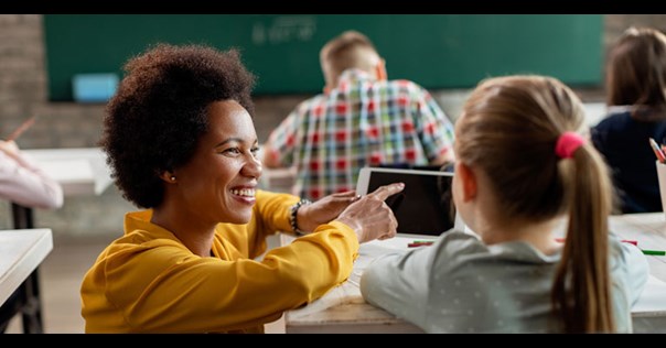 Teacher helping a pupil at a desk 