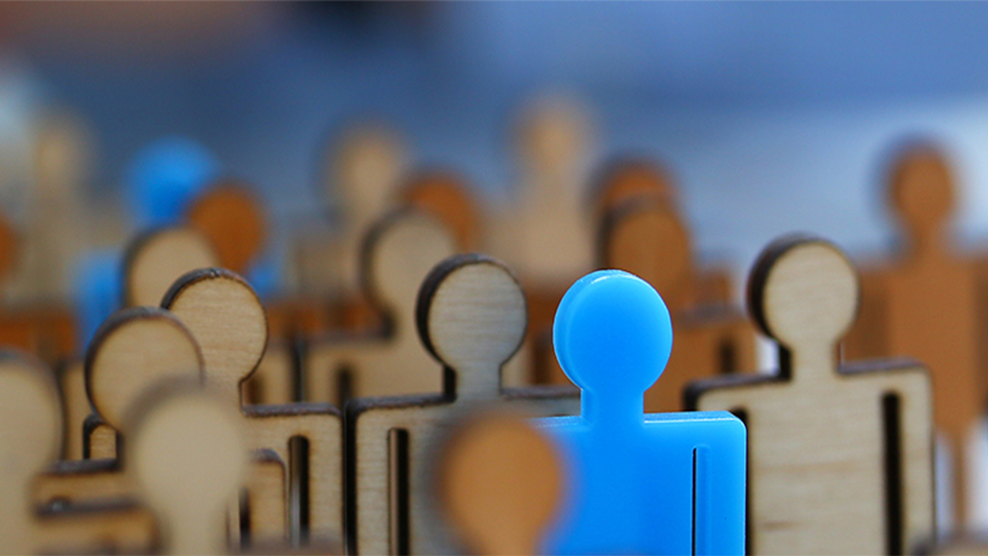 Wooden figures of people, one is bright blue and stands out