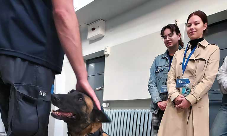 two students looking a dog with a handler 