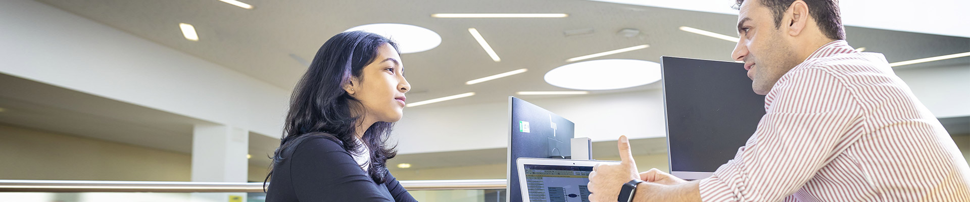 two students sitting at a desk with computers